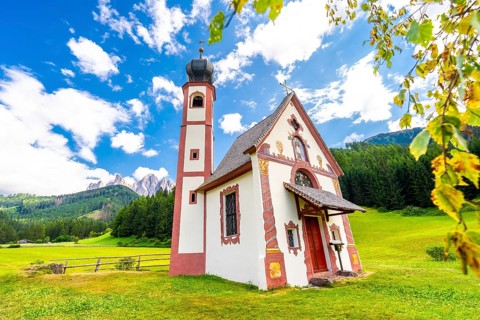 Charming st. Magdalena church nestled in a green meadow, with the majestic odle mountains and lush