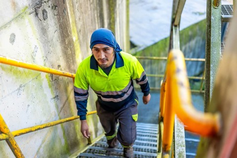 Top view of a latin man worker walking up stairs outside a recycling plant building