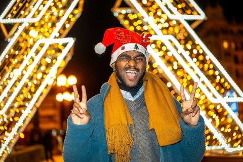 Portrait of a fun cool african young casual man gesturing success wearing a Santa hat at night in