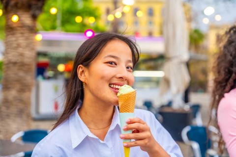 Close-up of a smiling chinese woman eating an ice cream in the city
