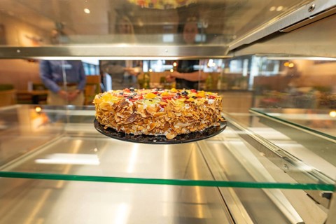 An artistically decorated cake with almond slivers and fruit in a glass display case, Cafe Kuh,