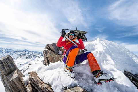 Happy mountaineer with ice axes and crampons on the summit of Piz Grialetsch in winter, Graubünden
