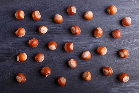 Pattern and texture made from hazelnuts on black wooden background, flat lay. top view