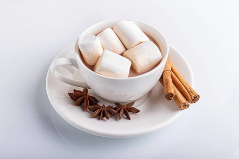 A cup of hot chocolate with marshmallow and cinnamon, isolated on white, closeup