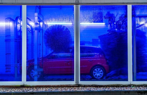 Car in an automatic car wash, car wash tunnel, cleaning foam is sprayed on, rotating brushes clean