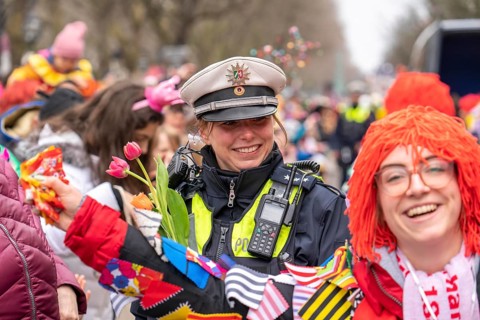 Rose Monday parade in Düsseldorf, policemen on duty at the street carnival, with flower