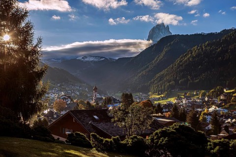 The mountain village of Ortisei in Val Gardena at sunrise, surrounded by wooded mountains and