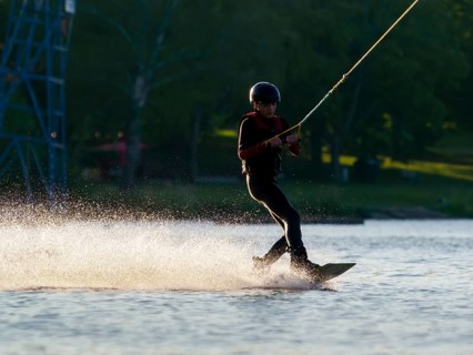 Young man with wakeboard in lake, water sports, water skiing in wakepark