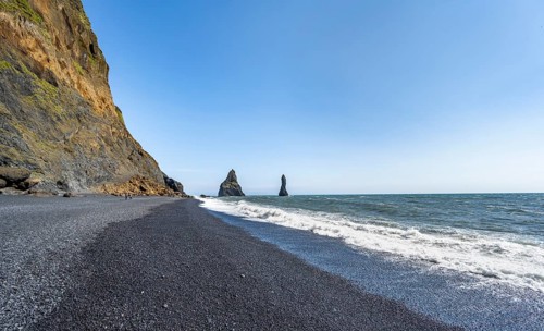 Black beach with cliffs, rock Reynisdrangar in the water, at Reynisfjara beach, Vik, South Iceland,