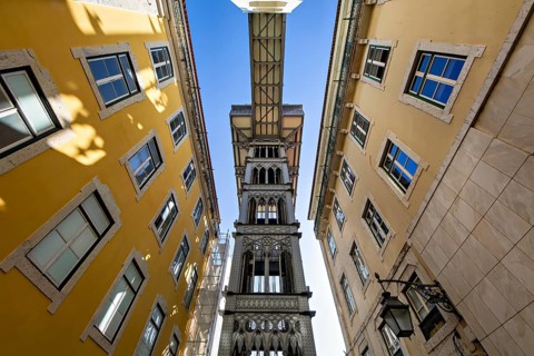 View from below of the Santa Justa Lift, an historical elevator in Lisbon, contrasting with the