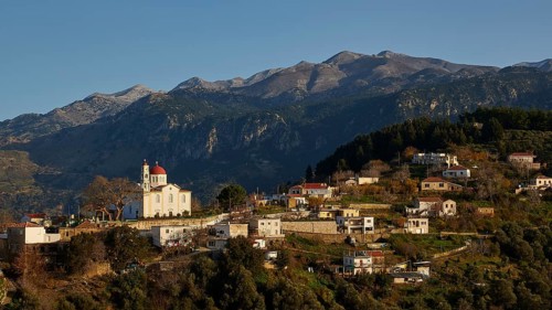 A small village in the mountains with a striking church at sunset, surrounded by mountains, Lakki