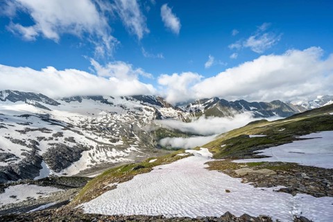 Mountain landscape with snow fields and high fog in the valley, summit Hoher Weißzint and