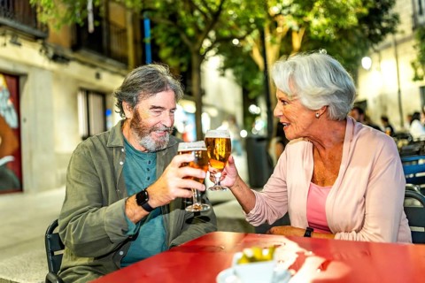 Senior couple toasting in a sidewalk bar in the city of Madrid