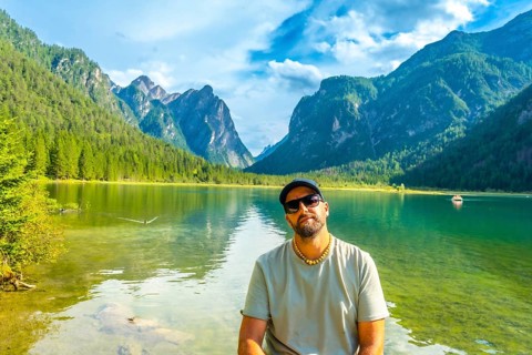 Tourist relaxing by lake dobbiaco, surrounded by the stunning peaks of the dolomites on a beautiful