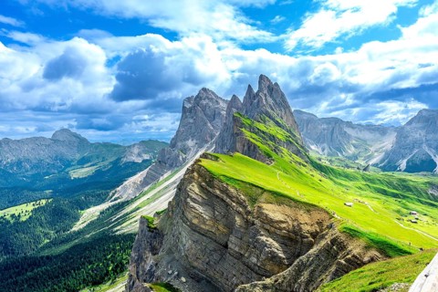 Hiking trails wind through lush green valleys beneath the majestic peaks of the seceda mountains in