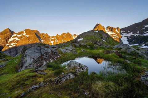 Rocky mountain peaks with reflection, small pond in moor landscape at Trollfjord Hytta, mountain
