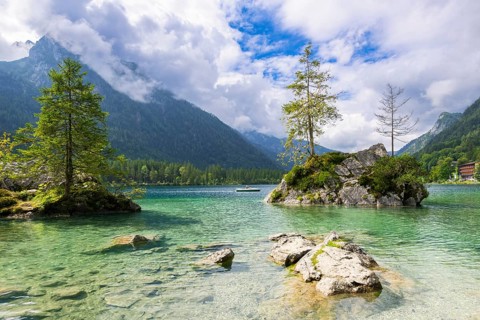 Hintersee near Ramsau with clear green water, surrounded by forests and mountains under a cloudy