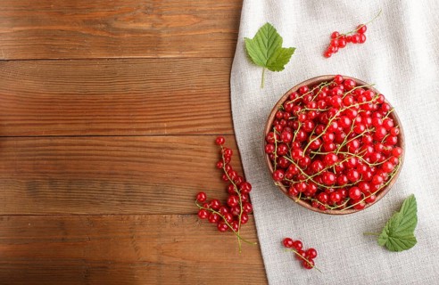 Fresh red currant in wooden bowl on wooden background. top view, flat lay, copy space