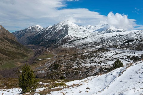 Weitläufiges Tal in den Bergen, teils mit Schnee bedeckt, unter blauem Himmel, nördlich von El Pas