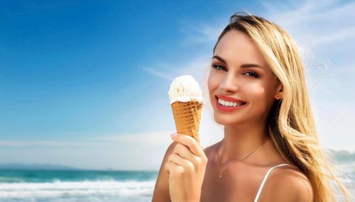 A blonde woman enjoys eating an ice cream in a cone