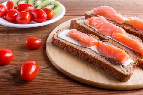 Smoked salmon sandwiches with butter on wooden background. cherry tomatoes. top view, close up