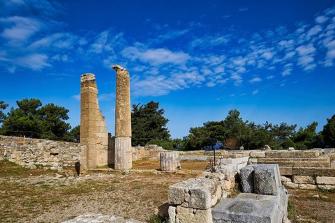 Two ancient columns amidst ruins and stone walls under a clear blue sky, Temple of Apollo, Kamiros,