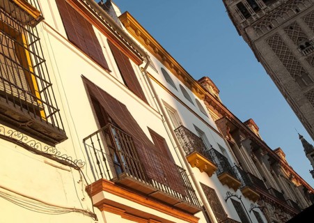 Late afternoon golden sunlight falling of historic houses in Placentines street, central Seville,