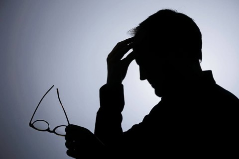 Symbolic photo on the subject of overload. Silhouette of a man rubbing his aching head. Berlin,