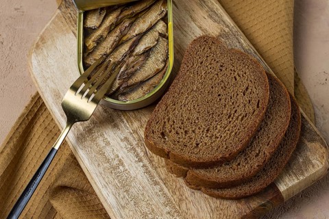Sprats in butter, with black bread, canned smoked fish, open, close-up, top view, no people