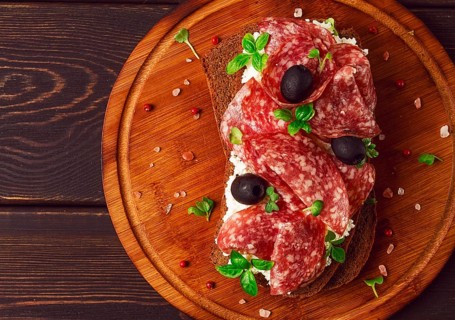 Sandwich, grain bread, with cream cheese and salami, black olives, micro-greens, top view,