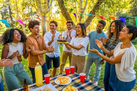 Happy young caucasian woman carrying a birthday cake while celebrating birthday in a park with