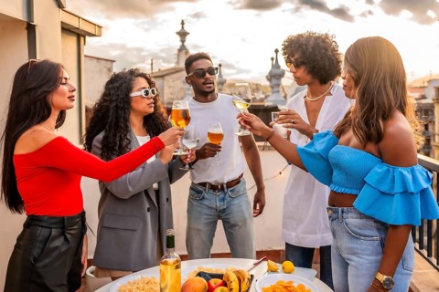 Multi-ethnic friends toasting on evening party in a city rooftop