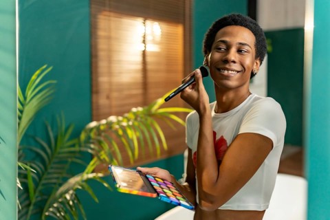 Reflection in the mirror of a transgender young latin man making up at home