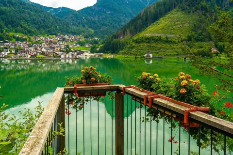Wooden balcony with flower boxes overlooking the picturesque village of alleghe, reflecting on