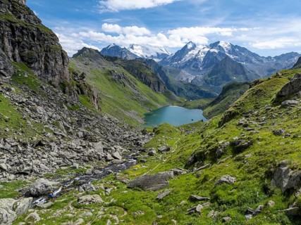 Mountain stream and mountain lake Lac de Louvie with glaciated summit of the Grand Combin, Val de