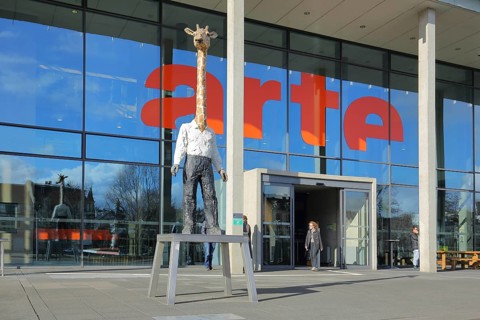 Entrance to the modern building of the ARD and ZDF broadcasting station Arte with sculpture Giraffe