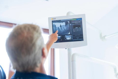 A person points to a screen with an X-ray image in a medical environment, dental practice, Germany,