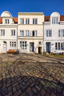 Historic houses, facades with windows, roofs with red roof tiles and dormers, cobblestone pavement,