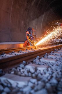 Night-time welding in the tunnel with flying sparks and protected workers, rail welding, track