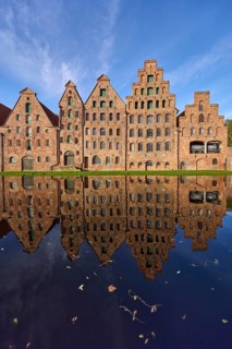 Historic salt warehouses, brick buildings reflected on the water surface of the Trave, blue sky