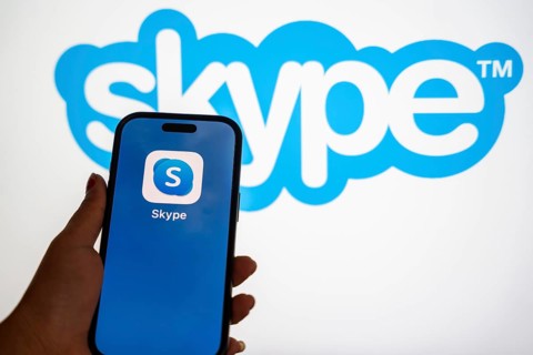 In this photo illustration, a person holds a mobile phone displaying Skype application, in