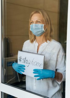 Woman with medical mask holding stay home notebook window