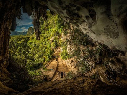 Photo of greenery and cave famous for paintings of wild animals and hand markings with petroglyphs