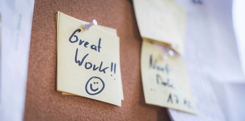 Close up of pinned note ?Great work? on cork board