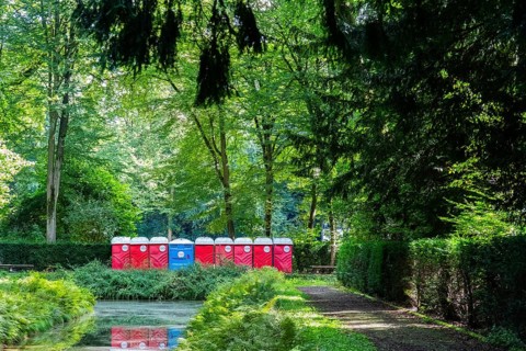 A row of red and blue toilet blocks in the park after an event, Düsseldorf, Germany, Europe