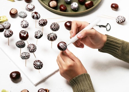 Chestnuts painted with white acrylic pen. Creative autumn decoration with natural material.