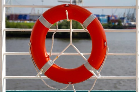 An orange lifebuoy hangs from a white railing with a view of a harbour, Hamburg, Germany, Europe