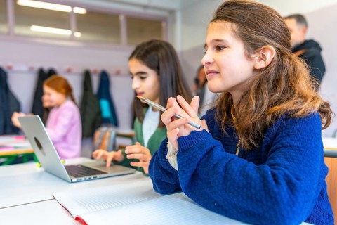 Smart young female students thinking and learning using laptop computer and notebook in elementary
