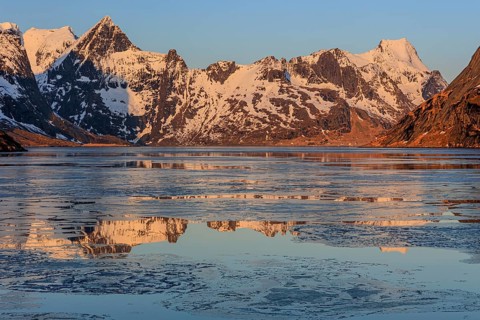 Fjord with ice floes in front of steep mountains, reflection, morning light, KjerkfjordeWinter,