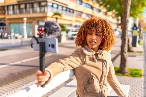 Latin female beuty and young vlogger streaming online sitting on urban stairs in a sunny autumn day